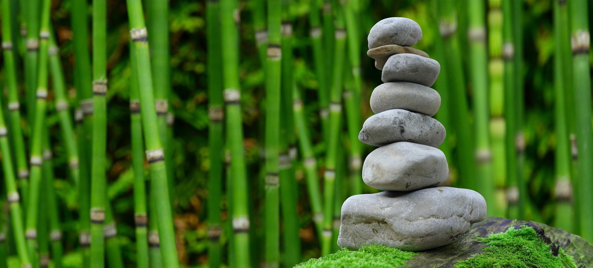 Ein Steinstapel vor Bambus. Sieben kleine rund Steine bilden einen Turm.